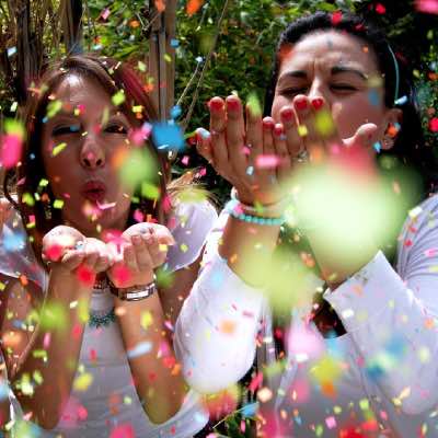 Women at an event or special occasion, enjoying themselves by blowing handfuls of confetti paper