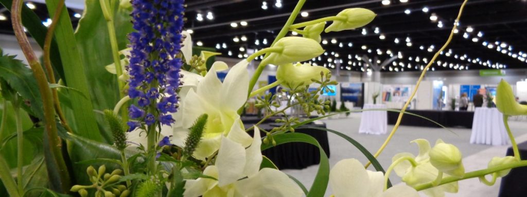 Trade show image, lots of bright lights and flower display in the foreground