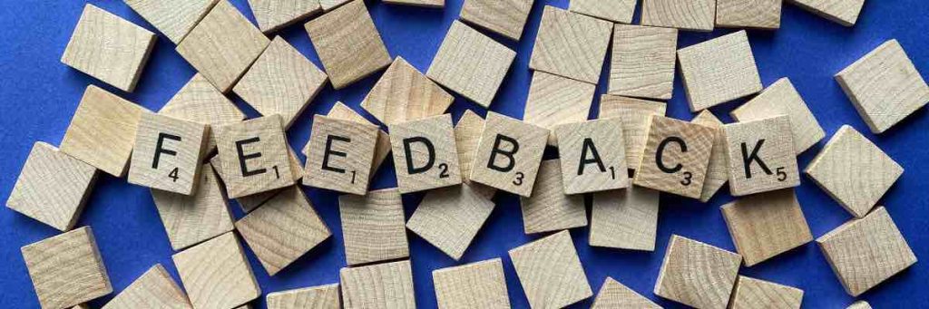 Scrabble game pieces scattered on a blue background showing the word feedback to mean feedback on an event